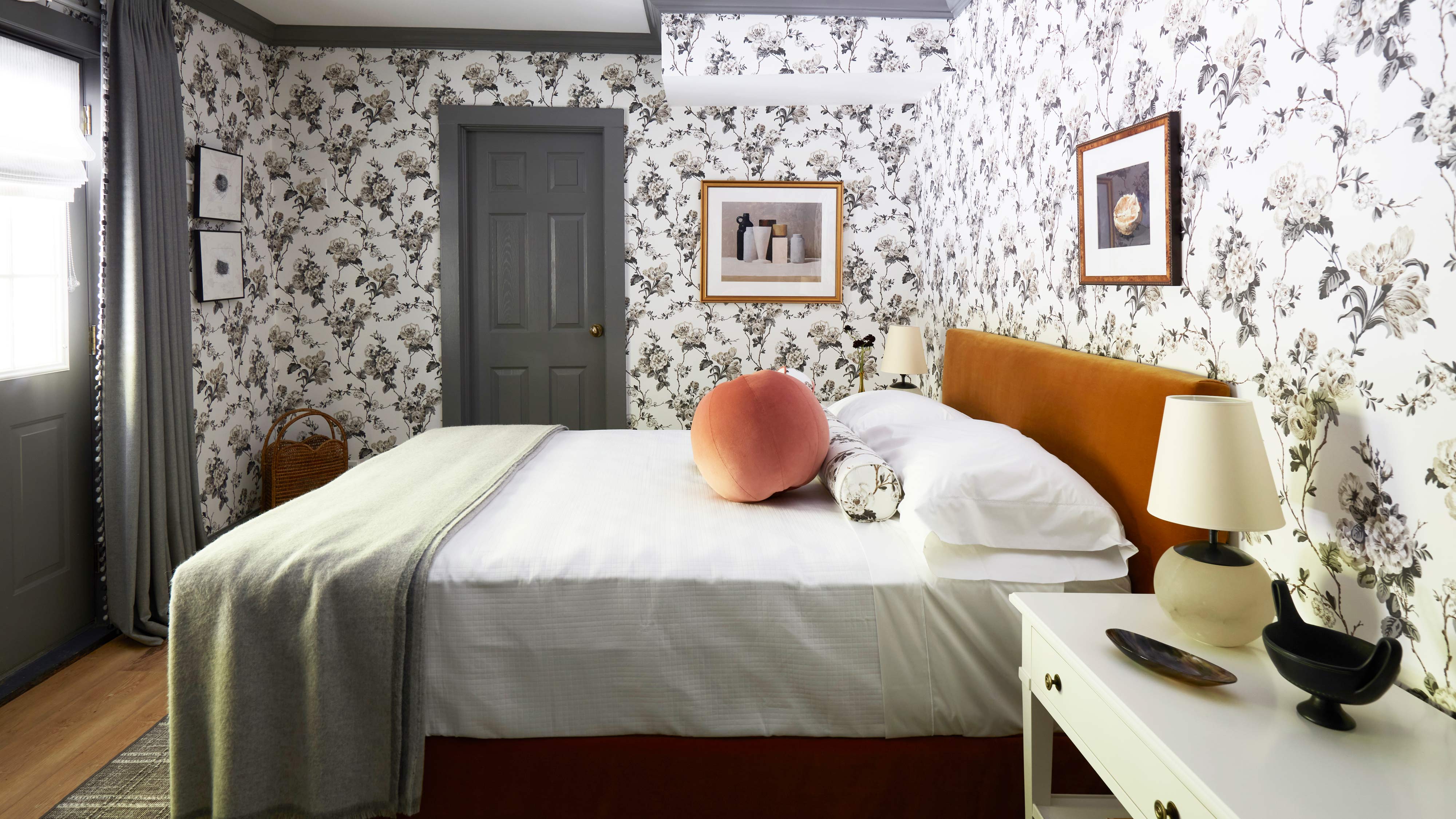 A bedroom with floral wallpaper, a bed, and a door.
