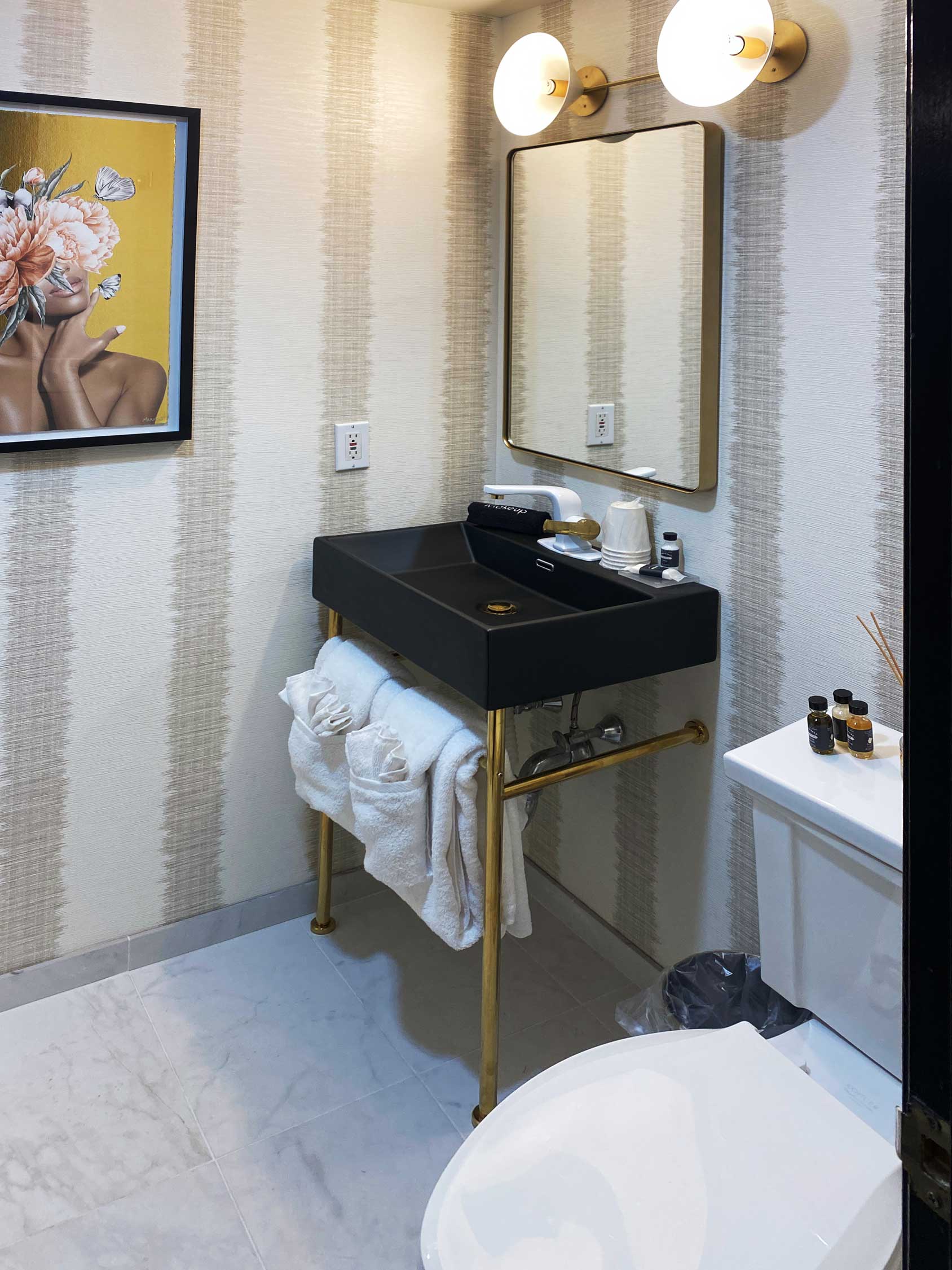A small bathroom with a black sink, a framed picture, and a toilet.