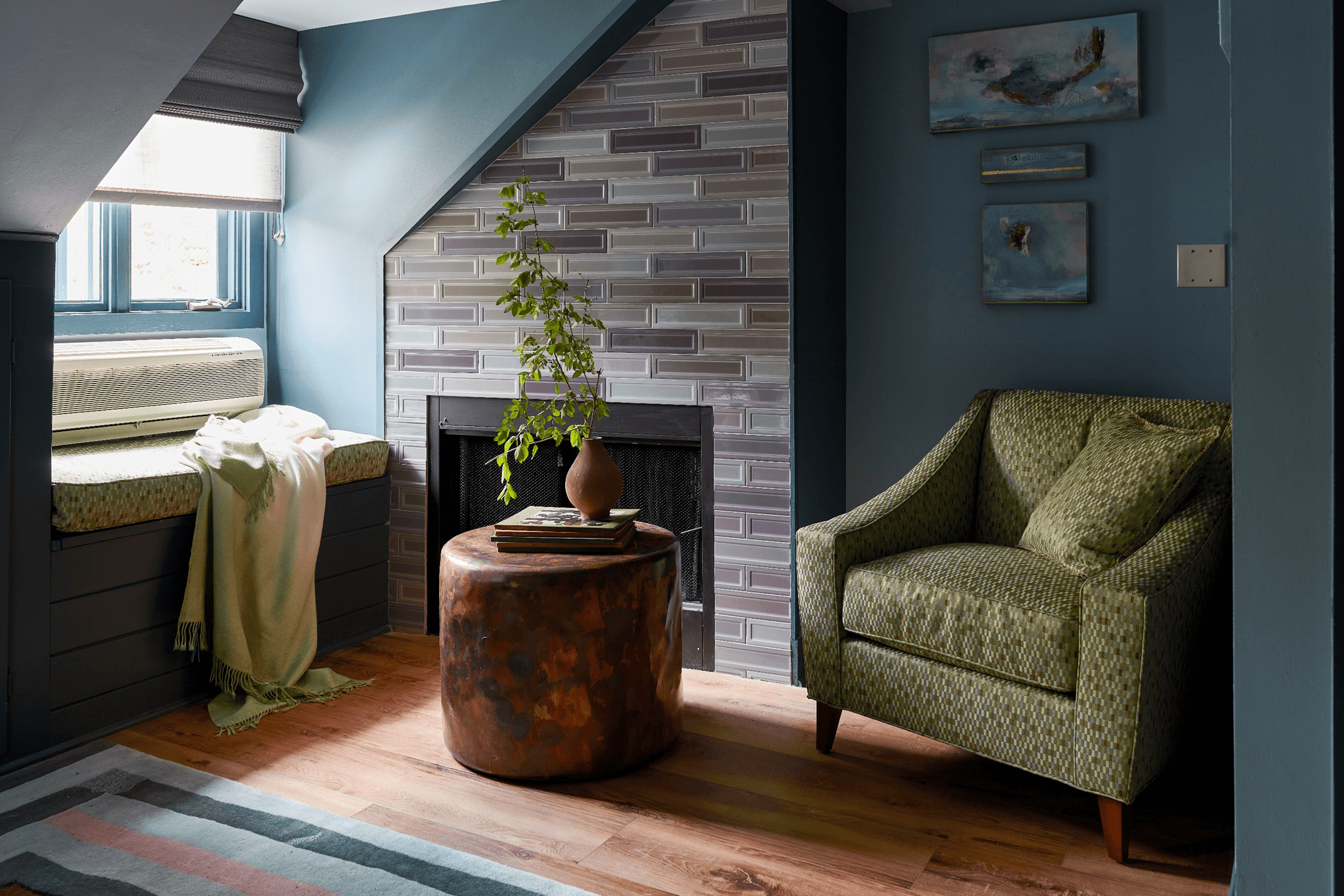 A sitting area with a fireplace, a green armchair, and a window seat.