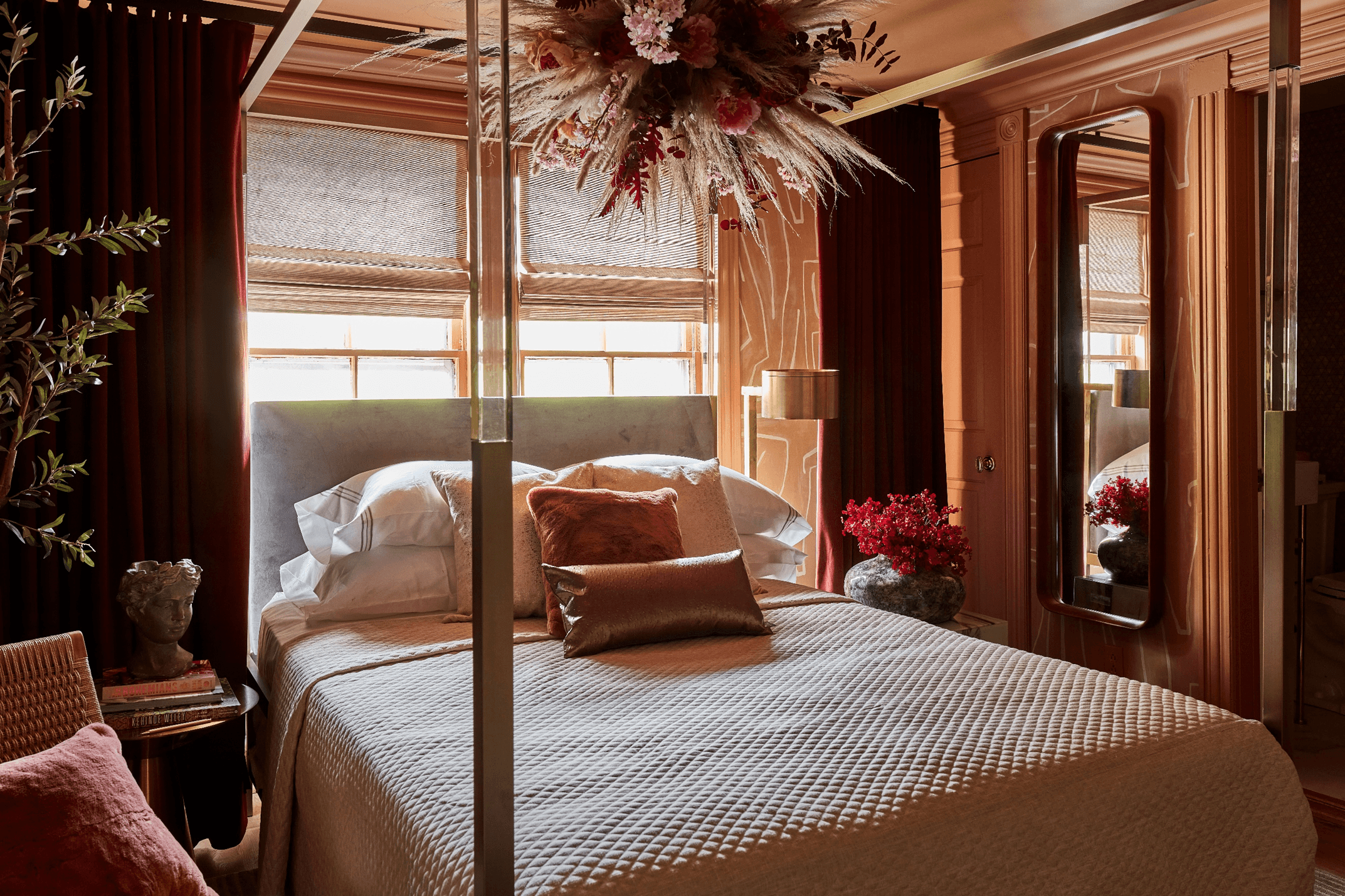 A bedroom with a four-poster bed, floral arrangement, and red accents.