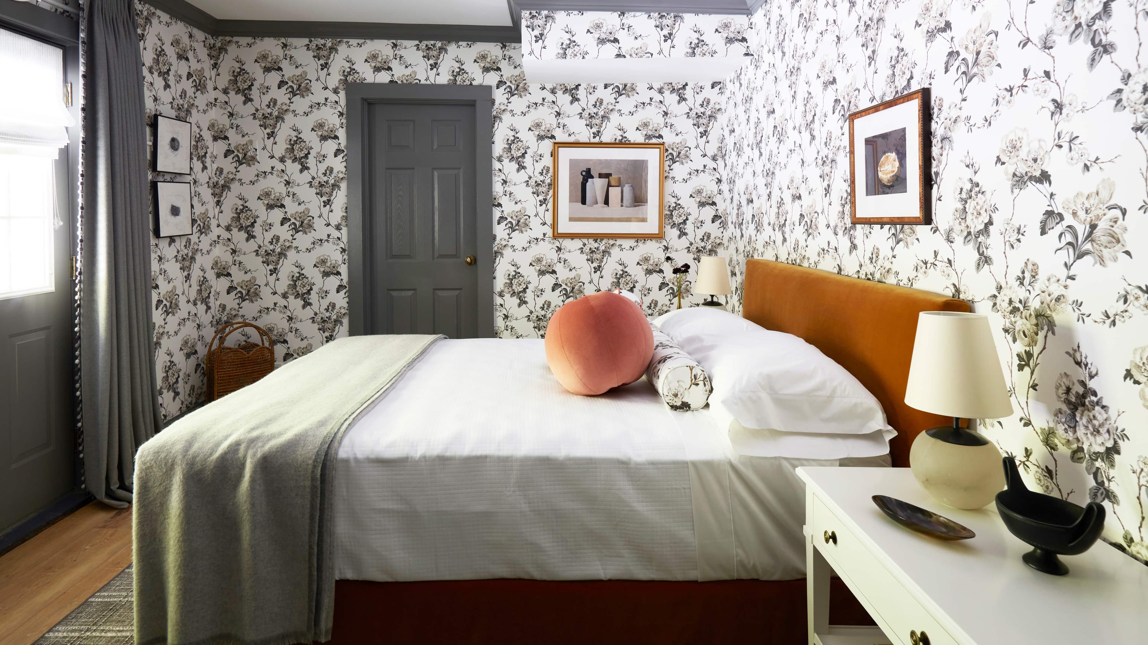 A bedroom with floral wallpaper, a bed, and a door.