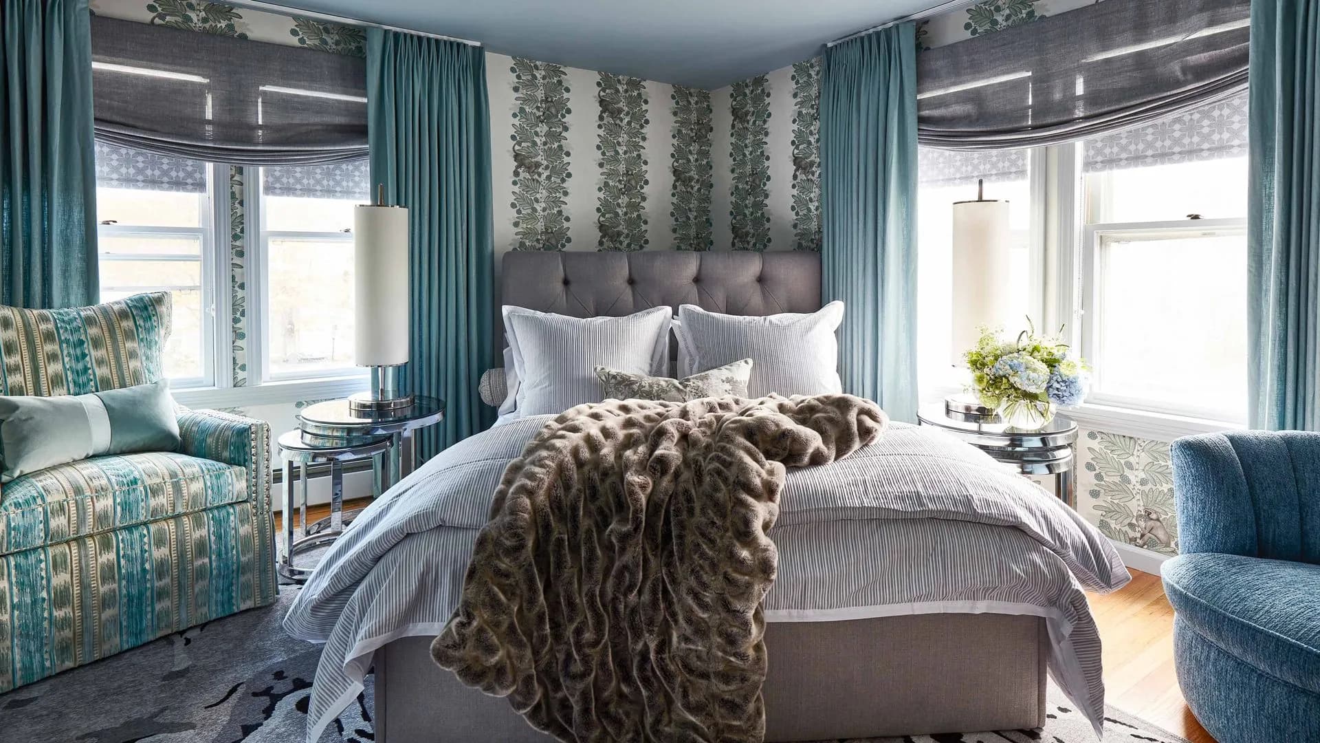 Modern bedroom with blue tones, patterned wallpaper, and a plush throw blanket.