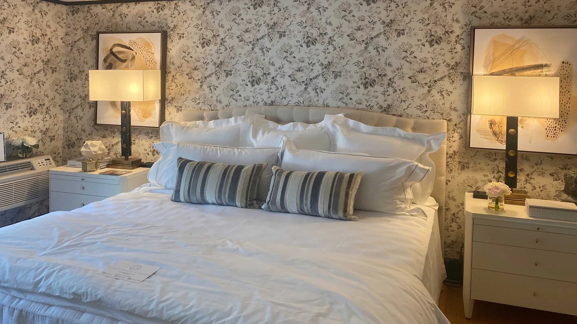 Serene bedroom with floral wallpaper, tufted headboard, and soft lighting from bedside lamps.