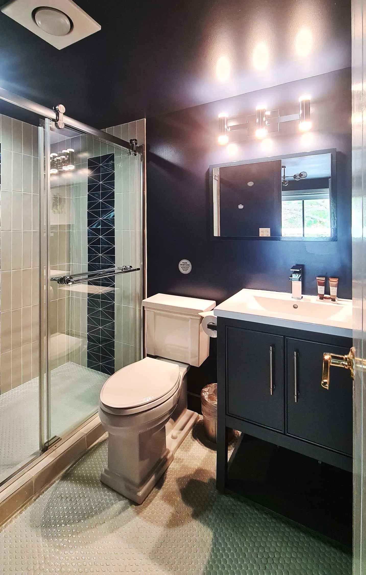 Modern bathroom with dark walls and glass shower.
