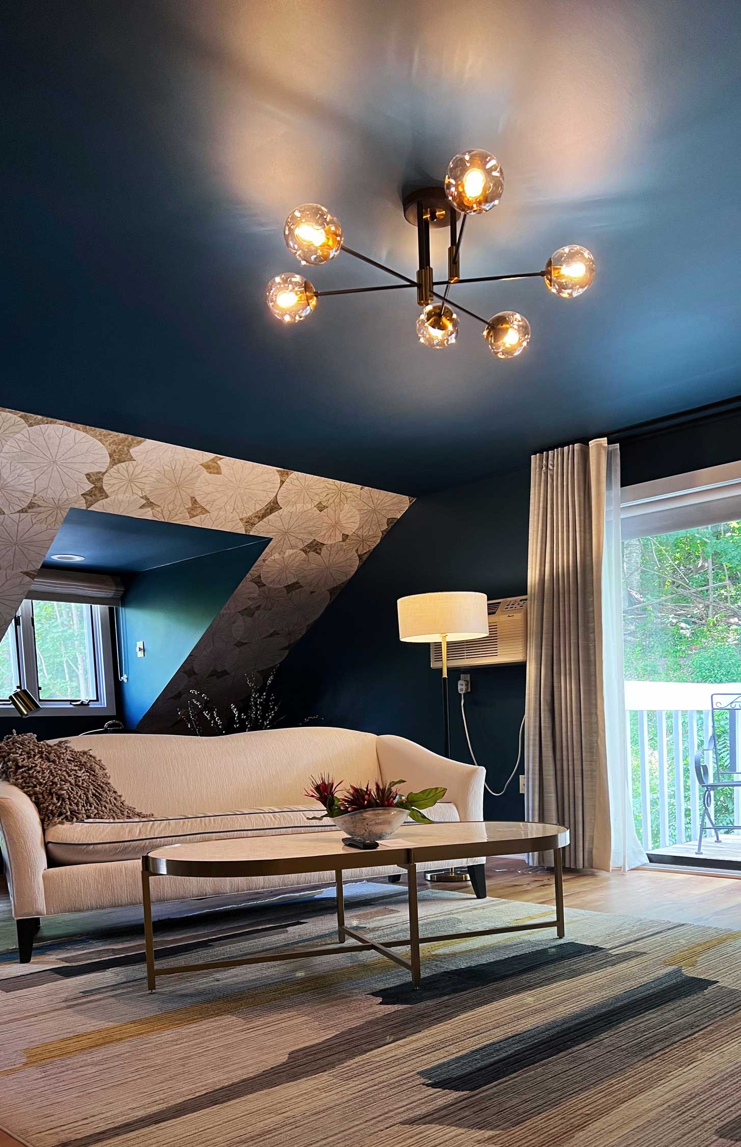 A living room with a dark blue ceiling, a sofa, a coffee table, and a unique chandelier.