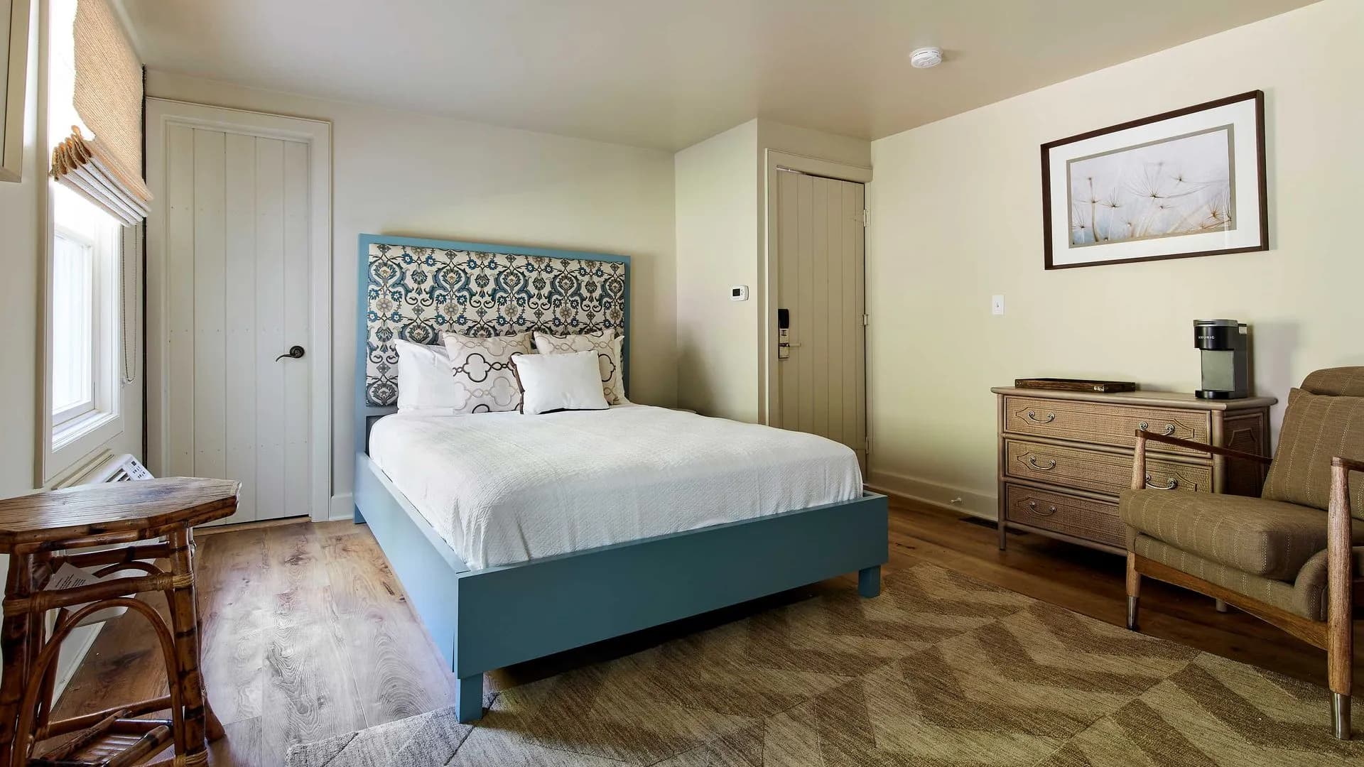 Small bedroom with blue bed frame, neutral walls, and patterned rug.