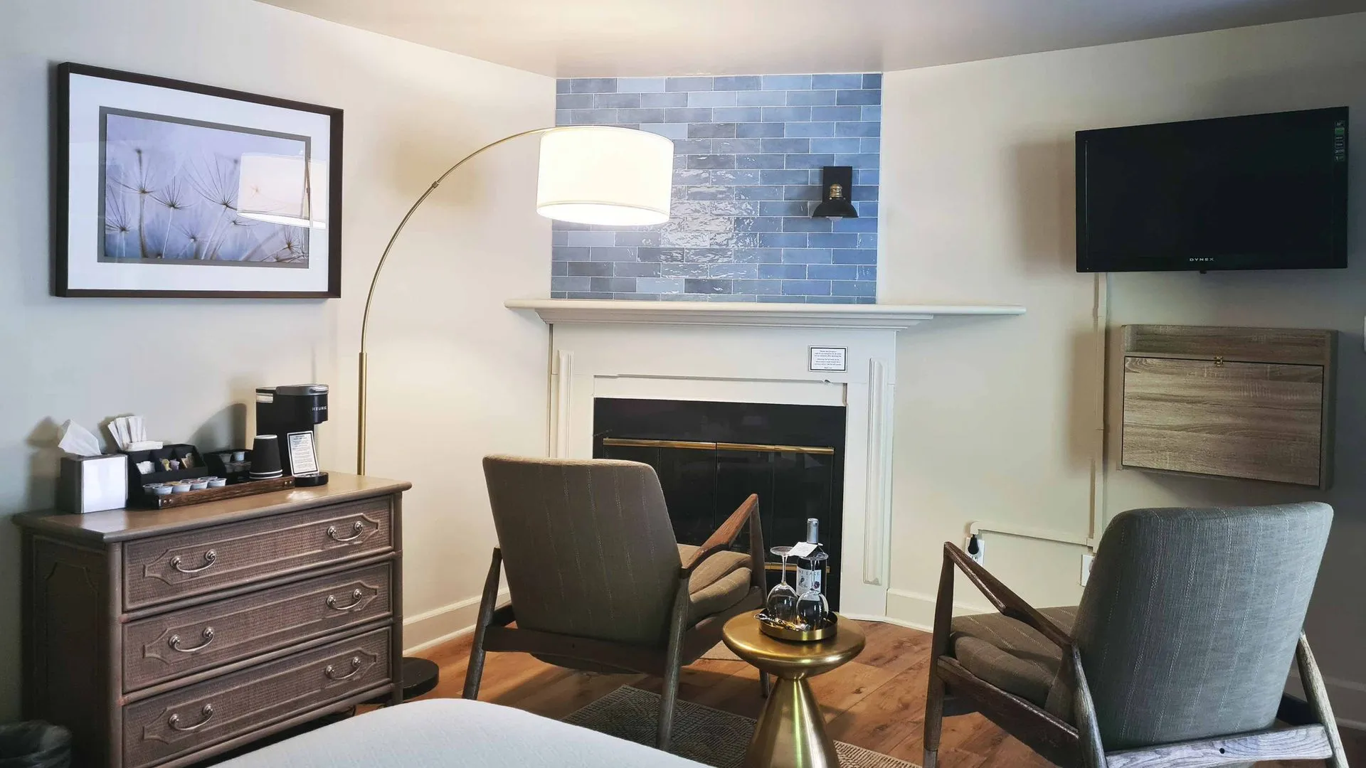 Sitting area with fireplace, TV, two armchairs, and a coffee station.