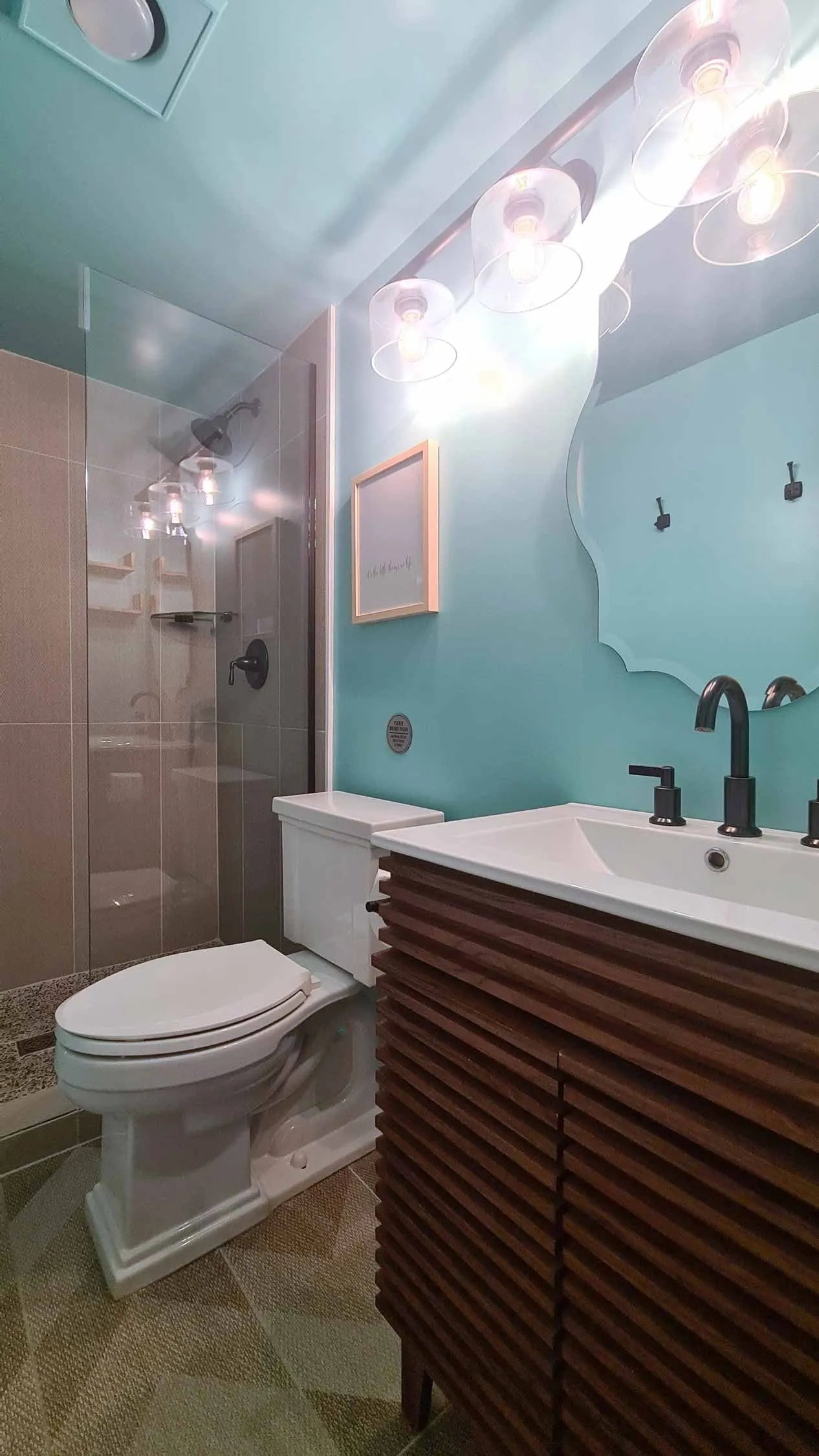 Modern bathroom with blue walls, unique vanity, and glass shower.
