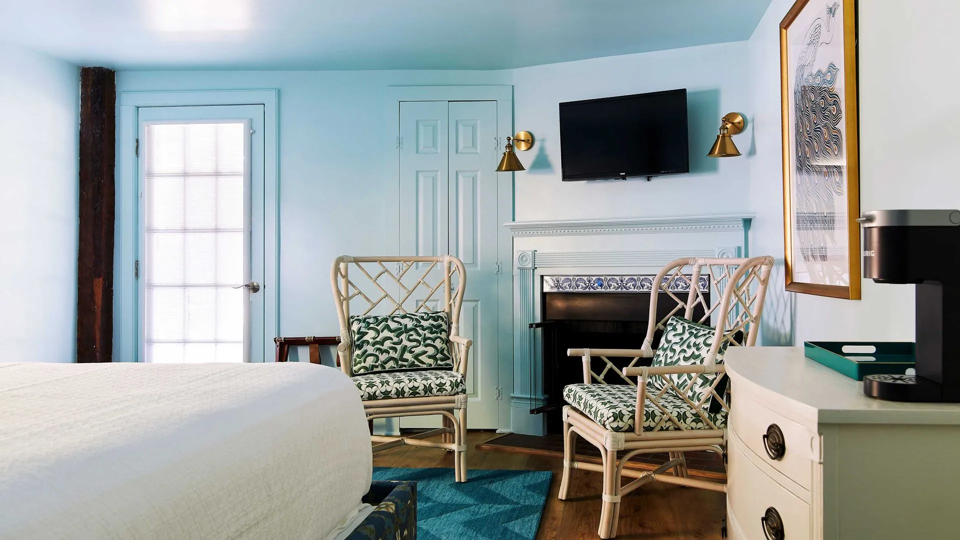 turqouise color rug, two wicker chairs, and a mounted tv above a fireplace