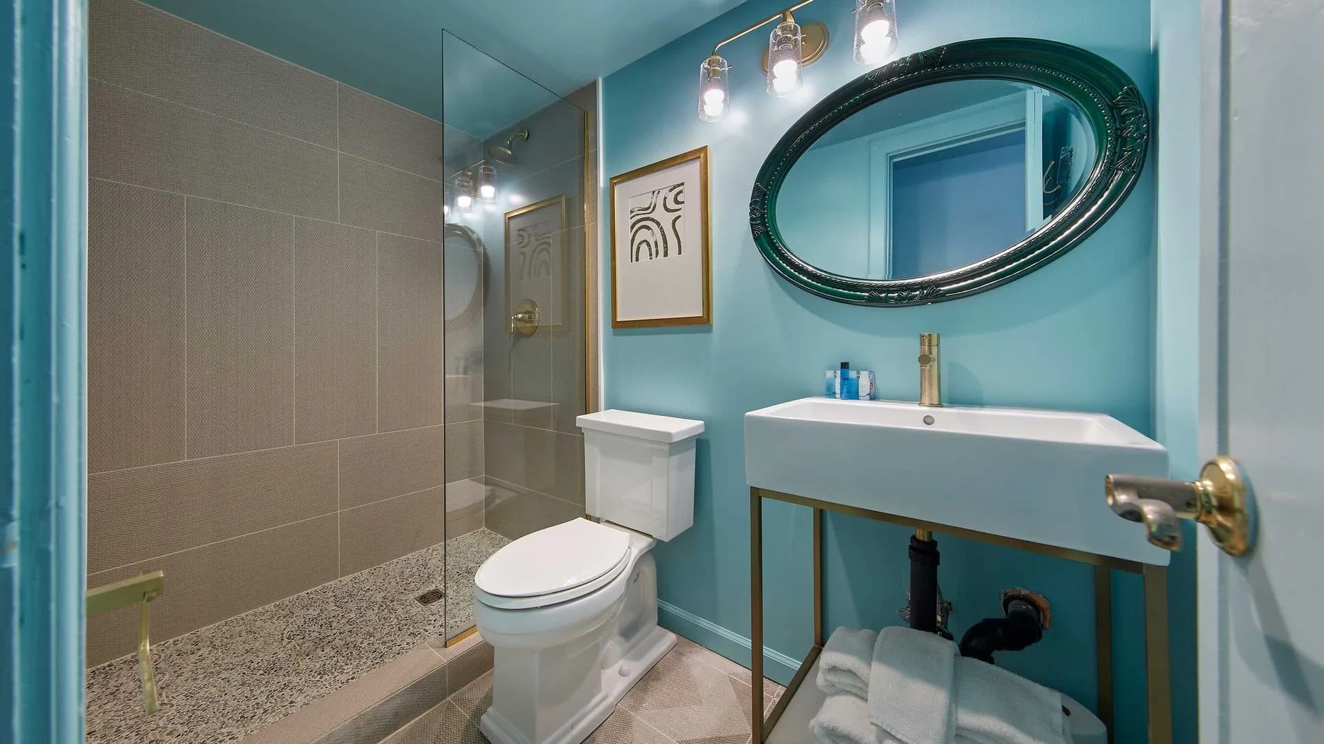 Bright blue bathroom with faucet sink, oilet, and glass walk-in shower