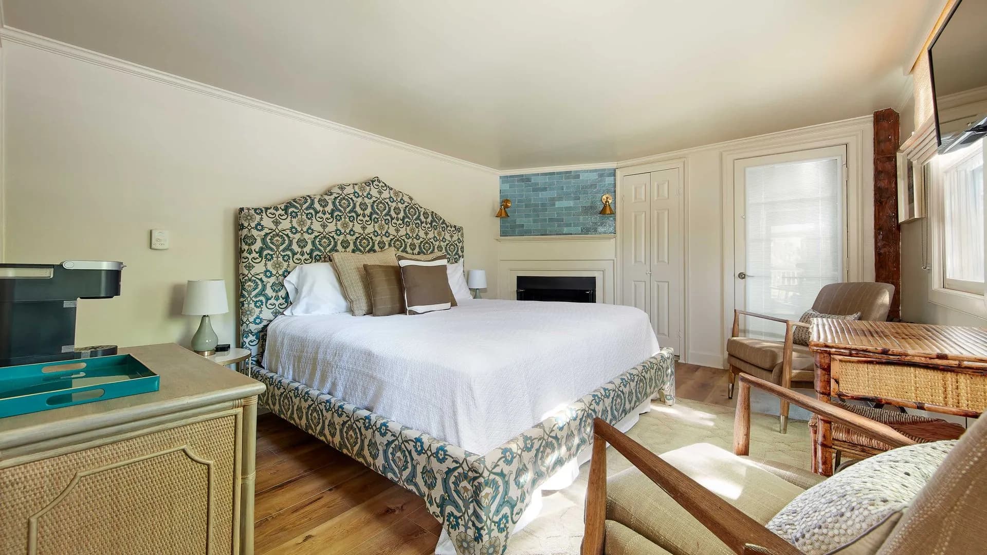 Blue pattern bedframe with all white bedding, white walls, a fireplace in the corner