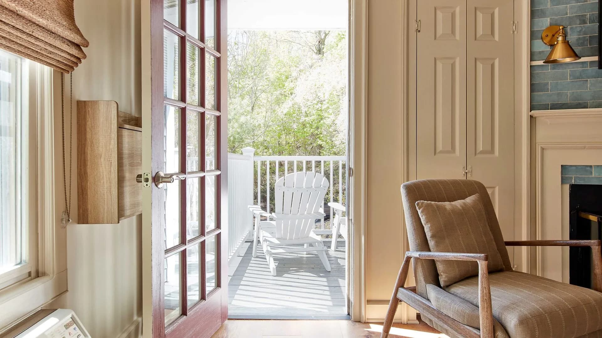 Balcony view with white rocking chair through open French doors.