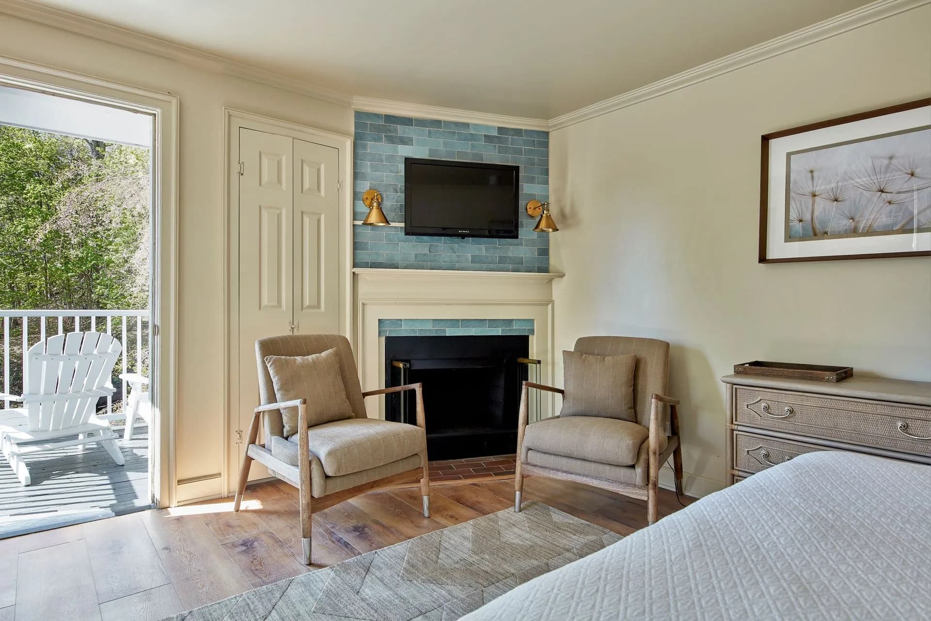 Bedroom with balcony view, fireplace, TV, and two armchairs.