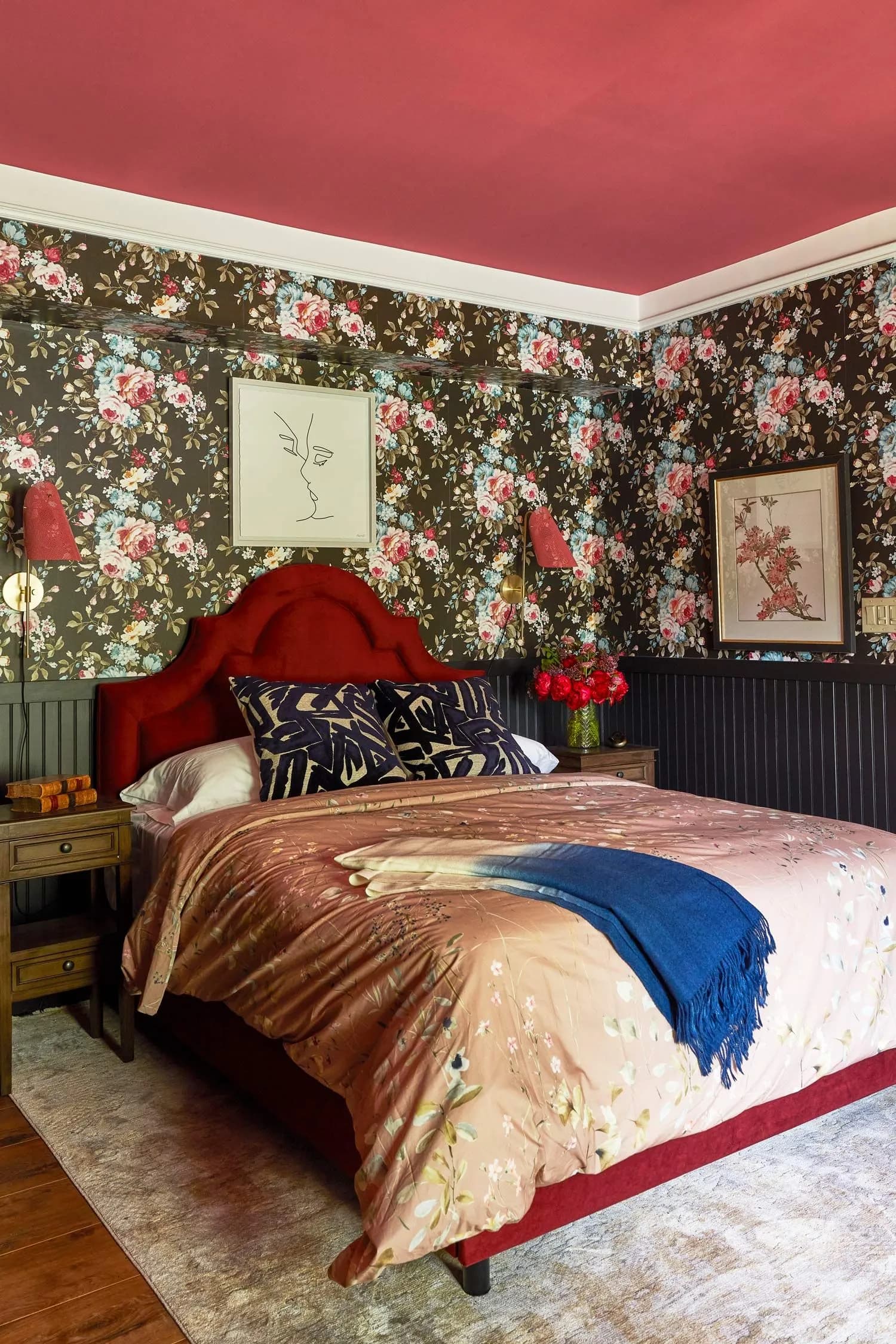 Eclectic bedroom with floral wallpaper, red ceiling, and unique artwork.