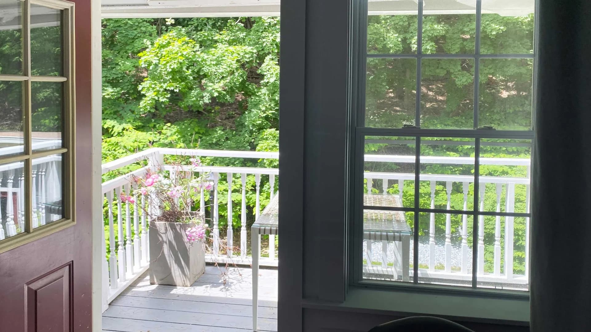 daytime view of a outside porch with 1 entrance and window where there is a table and chairs.