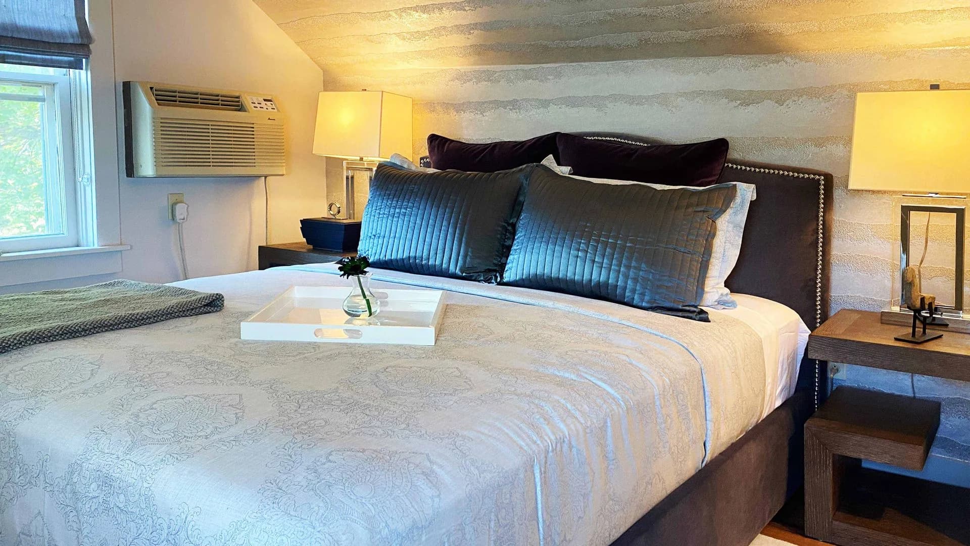 Serene bedroom with neutral tones, tufted headboard, and soft lighting.