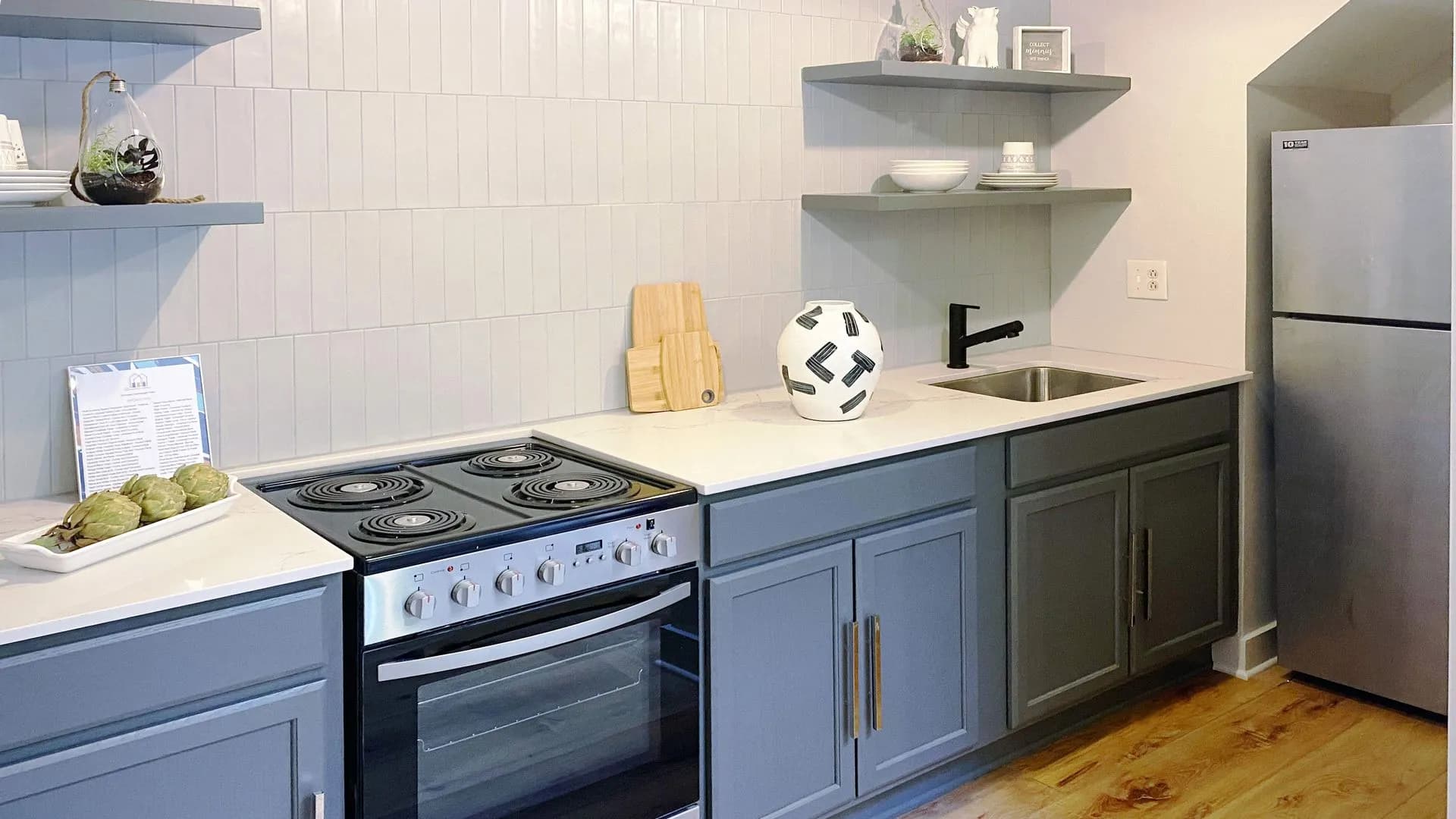 Modern kitchen with gray cabinets, white countertops, and open shelving.