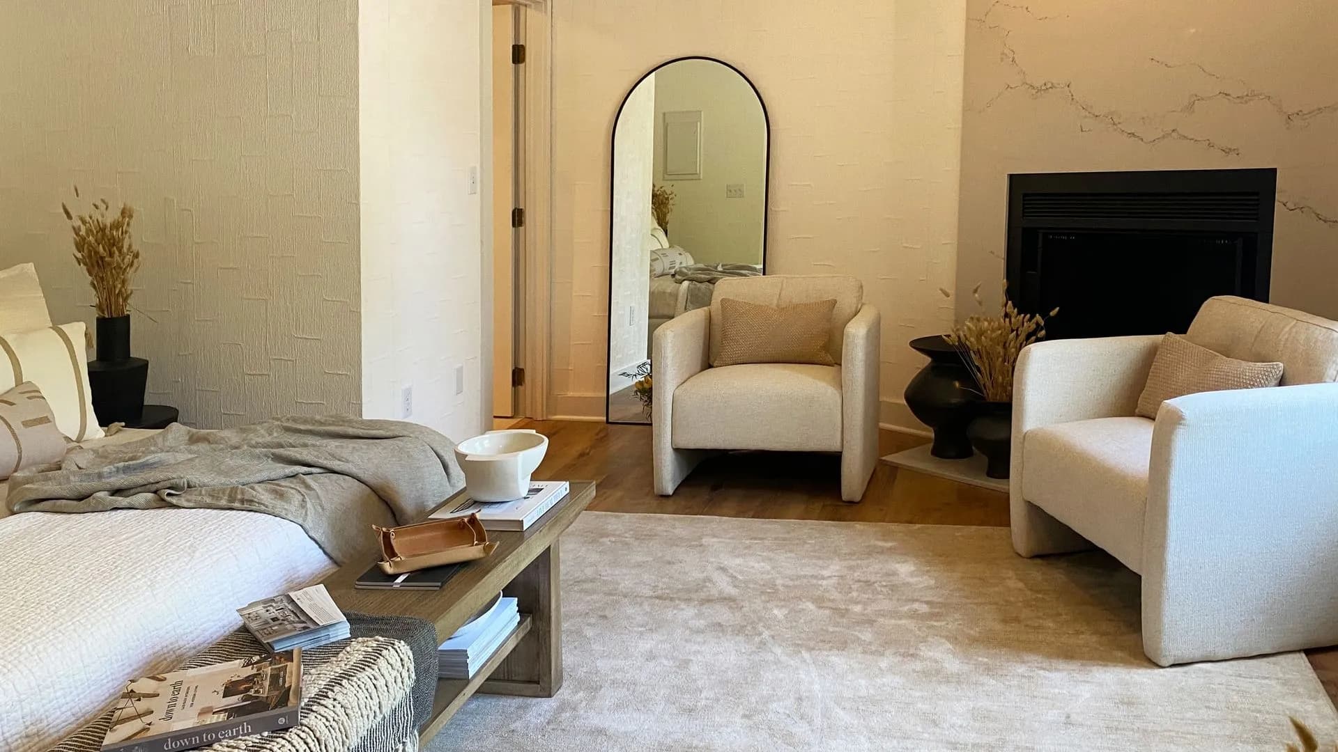 View of a sitting area with two chars a tv behind the chairs and mirror on the wall.