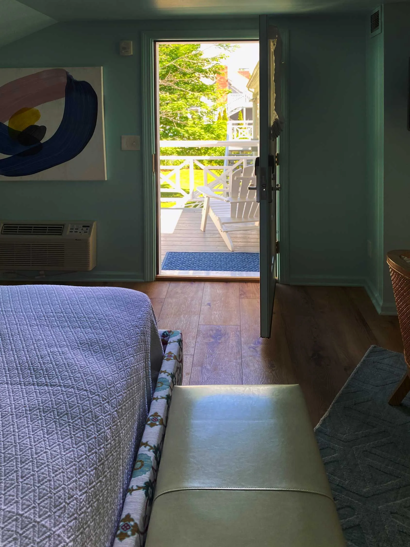 Balcony view with white Adirondack chairs through open door from blue room.