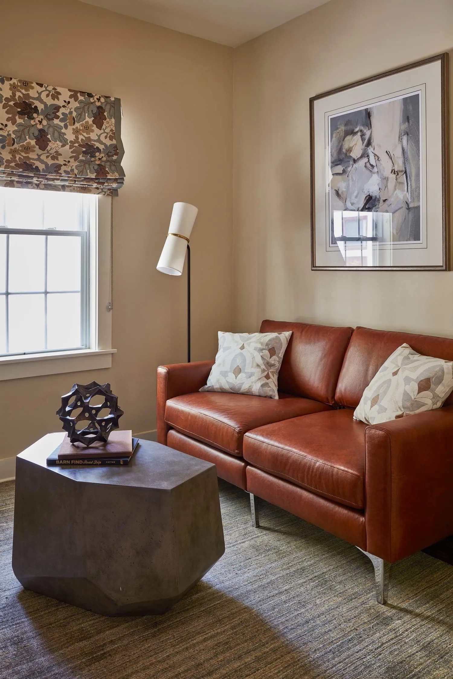 modern brown leather couch with a stone coffee table and artwork hanging above the couch