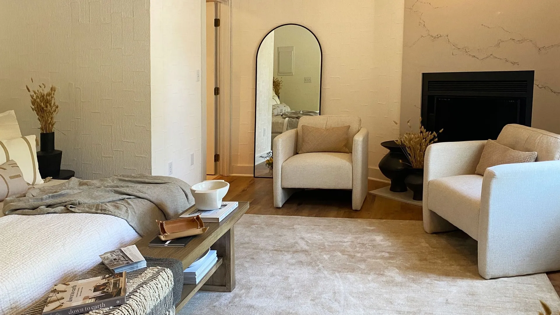 View of a sitting area with two chars a tv behind the chairs and mirror on the wall.