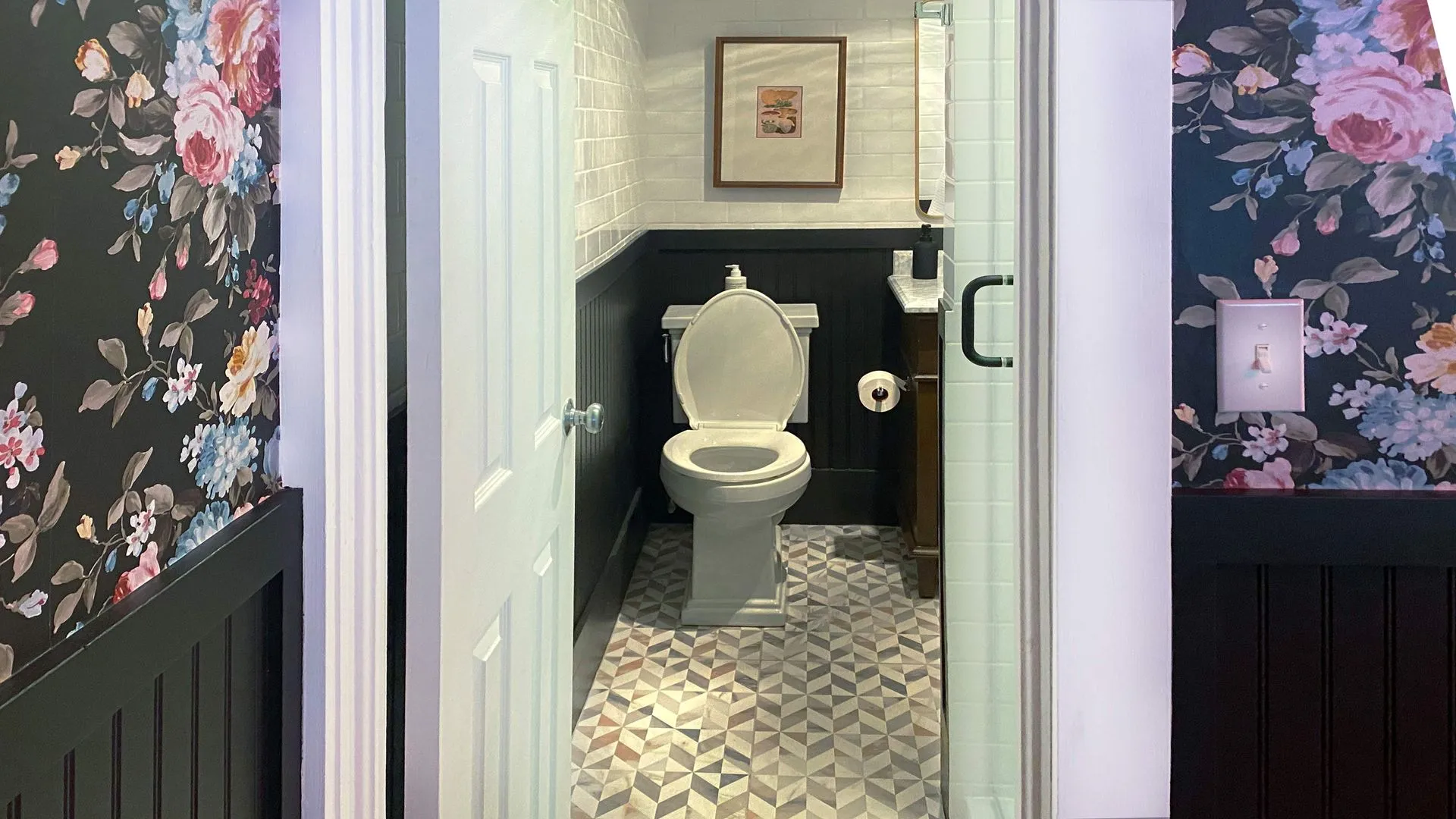 Bathroom with floral wallpaper, half-wall paneling, and patterned tile floor.