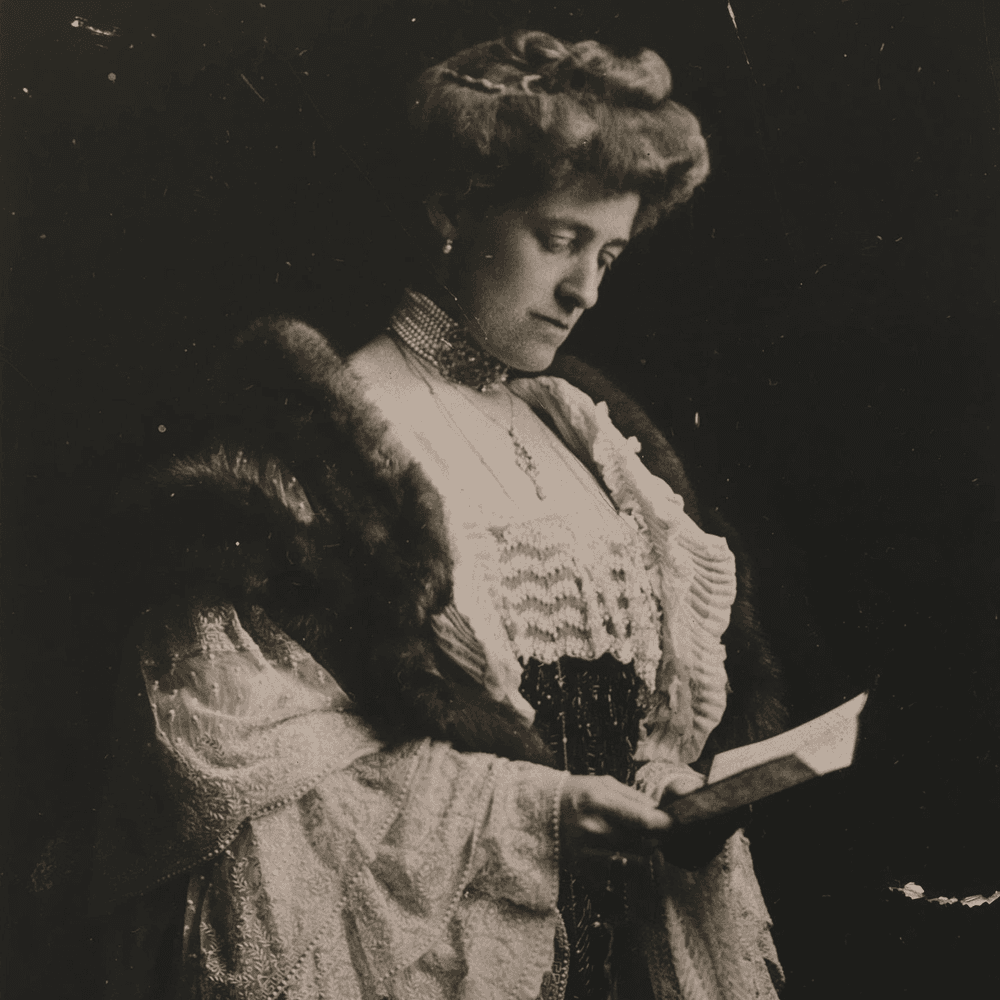 A woman in historical dress holding a book, looking down thoughtfully.