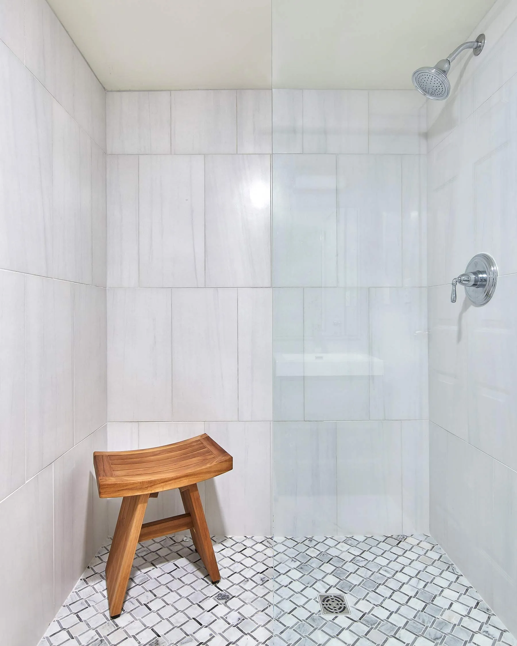 wooden stool in a glass door walk-in shower