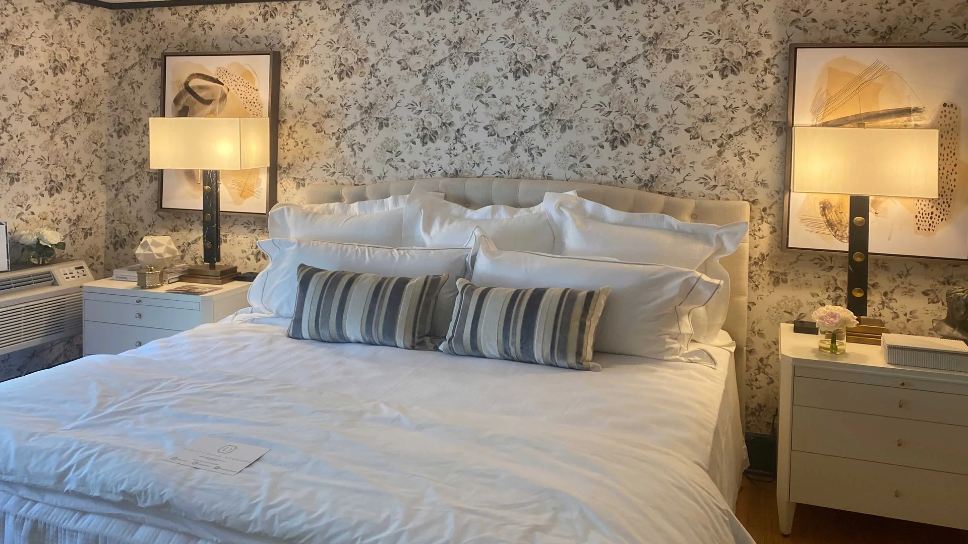 Serene bedroom with floral wallpaper, tufted headboard, and soft lighting from bedside lamps.